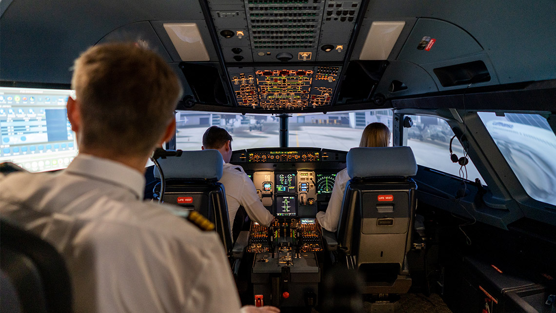 Blick in einen Cockpit-Simulator mit zwei Piloten und einem Ausbilder