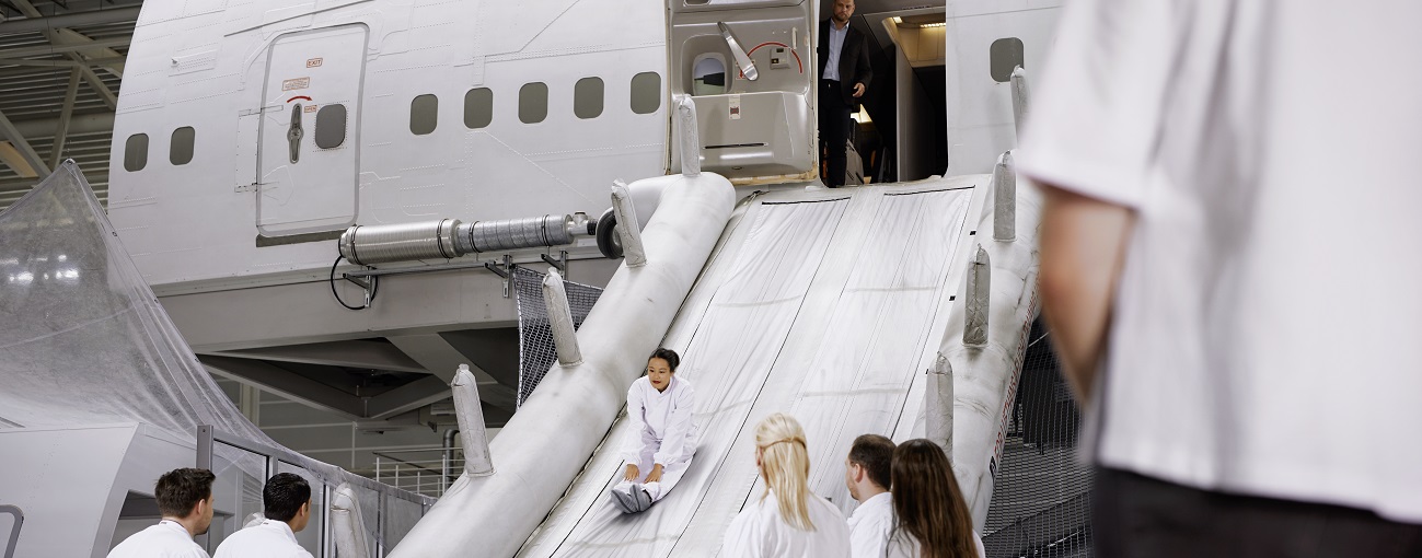 During a training scenario, a person slides down the emergency slide of an aircraft mock-up